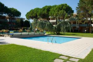 a swimming pool in a park with trees and a building at Solarium/piscina in Bibione