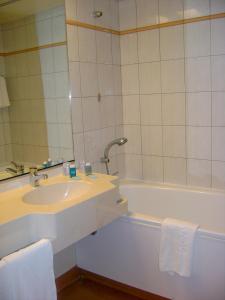 y baño con lavabo y bañera con espejo. en Hôtel des Thermes Les Dômes, en Vichy
