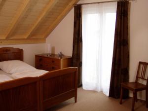 ein Schlafzimmer mit einem Bett, einer Kommode und einem Fenster in der Unterkunft Gästehaus am Sonnenfeld in Sommeri