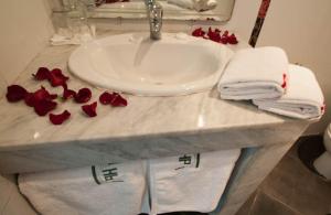 a bathroom counter with a sink and towels and red roses at Hotel De La Paix in Fès