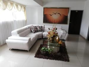 uma sala de estar com um sofá branco e uma mesa em Hotel Cafe Plaza em Tuluá
