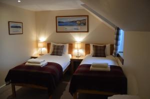 a small room with two beds and two lamps at Ness View Apartment in Inverness