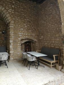 patio ze stołem i krzesłami oraz ceglaną ścianą w obiekcie Dar Camelia w mieście Sur