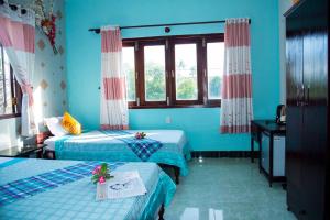 een blauwe kamer met 2 bedden en een raam bij Song Huong Hotel Mui Ne in Mũi Né