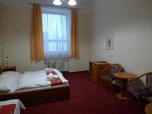 a room with a bed, a desk, and a chair at Hotel U Černého orla in Telč