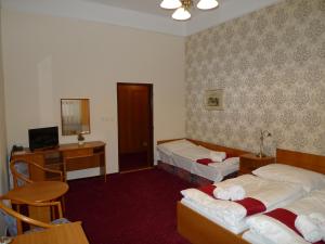 a hotel room with two beds and a television at Hotel U Černého orla in Telč