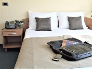 a suitcase sitting on top of a bed with a phone at Hotel Central Slavonski Brod in Slavonski Brod