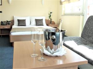 two wine glasses and a bucket on a table with a bed at Hotel Central Slavonski Brod in Slavonski Brod