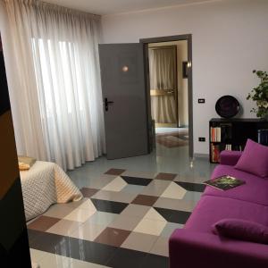 a living room with a purple couch and a checkered floor at Camere Mazara in Mazara del Vallo