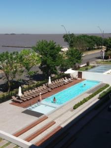 a swimming pool with lounge chairs and the ocean at Monoambiente 509, Dos Orillas in Colonia del Sacramento