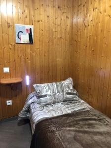 1 dormitorio con paredes de madera y 1 cama con almohadas en TRETRA 110, en Pas de la Casa