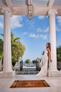 Una mujer con un vestido de novia parada frente a las columnas en Veggera Beach Hotel, en Perissa