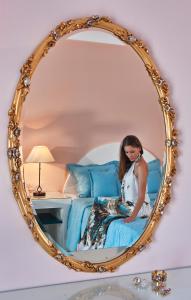a woman sitting on a bed in a mirror at Veggera Beach Hotel in Perissa