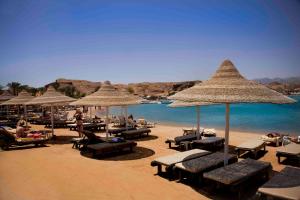 a beach with chairs and umbrellas and the water at Xperience St. George Sharm El Sheikh in Sharm El Sheikh