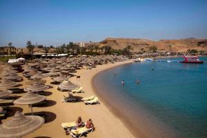 a beach with a bunch of umbrellas and people in the water at Xperience St. George Sharm El Sheikh in Sharm El Sheikh