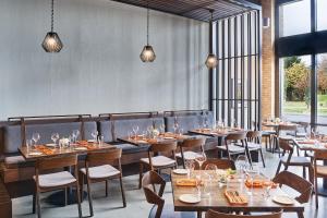 a restaurant with wooden tables and chairs and windows at The Bristol Hotel in Bristol