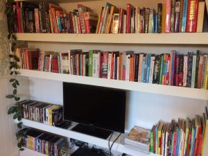 una estantería de libros llena de libros y un monitor de ordenador en Place to Bee (Kamers), en Cortrique