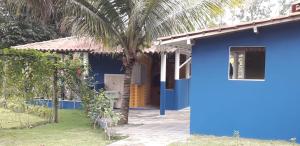 a blue house with a palm tree in front of it at Condomínio Canaã Cumuruxatiba in Cumuruxatiba