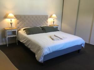 a bedroom with a large white bed with two lamps at L ANNEXE in Malaucène