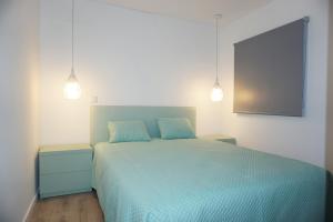 a bedroom with a bed with blue sheets and two lights at House 41 in Vila Nova de Famalicão