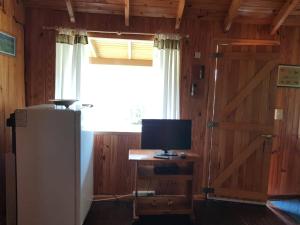 a room with a refrigerator and a window and a television at Nahuel Mapi Lodge in Pilolil