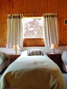 a bedroom with a bed with a window and two lamps at Nahuel Mapi Lodge in Pilolil