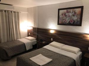 a hotel room with two beds and a picture on the wall at Hotel Masseilot in Santana do Livramento