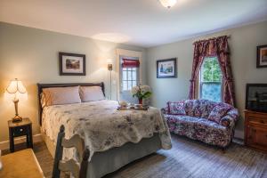 a bedroom with a bed and a chair and a window at Heartwood Inn in Drumheller