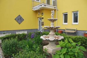 a fountain in a garden in front of a yellow building at Hotel & Restaurant Garda in Darmstadt