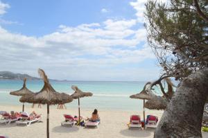 a group of people sitting in chairs on a beach at Hostal Brisa Marina in Port d'Alcudia