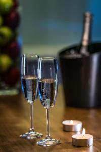 テッサロニキにあるGlossy Lodgeのシャンパン2杯、テーブルの上にキャンドル