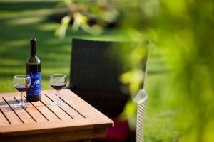 a bottle of wine and two glasses on a wooden table at Herdades Da Frupor - Casas De Campo in Brejao