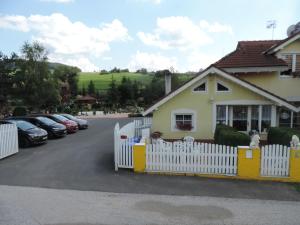 a yellow house with a white fence in a parking lot at Privat Janka in Tvarožná