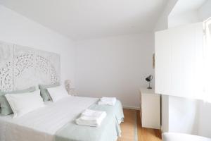 リスボンにあるDowntown Charming Apartmentの白いベッドルーム(白いシーツと枕付きのベッド1台付)