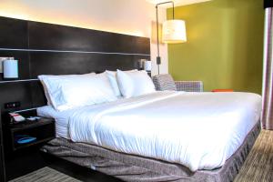 a large bed in a hotel room with a white bedspread at Holiday Inn Express Rochester - Greece, an IHG Hotel in Rochester