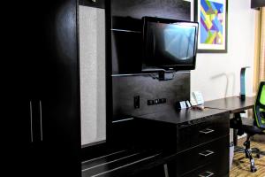 a black dresser with a tv and a desk at Holiday Inn Express Rochester - Greece by IHG in Rochester