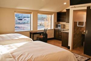 a bedroom with two beds and a desk and a kitchen at Iron Springs Luxury Lodge & Spa in Cedar City