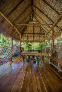 a dining area with a table and hammocks in a straw roof at El Chante Surf House in Santa Teresa Beach +54 photos