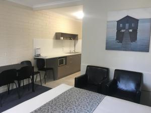 a room with a bed and chairs and a kitchen at Victor Harbor City Inn in Victor Harbor
