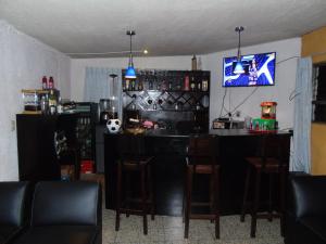 a bar with stools and a tv in a room at El Centro Hotel in Quetzaltenango