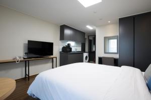 a bedroom with a white bed and a kitchen at New Songtan Hotel in Pyeongtaek