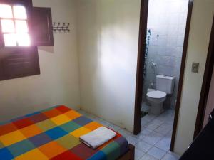 a bathroom with a colorful bed and a toilet at Casa de Praia em Carneiros in Tamandaré