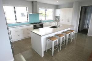 a kitchen with white cabinets and a white island with stools at Glenvue in Lake Tekapo