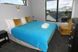 a bedroom with a bed with a blue blanket and a window at Glenvue in Lake Tekapo