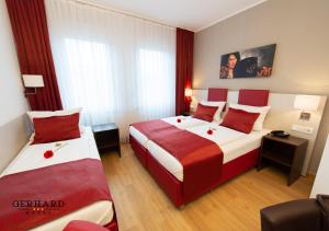 ニュルンベルクにあるホテル ゲルハルトのホテルルーム ベッド2台 赤い枕付