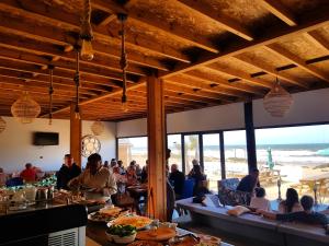 eine Gruppe von Menschen, die in einem Restaurant mit Strand sitzen in der Unterkunft Greenwave Ecolodge in Mirleft