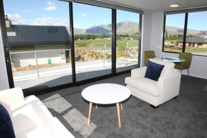 a living room with chairs and a table and large windows at Glenvue in Lake Tekapo