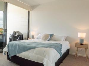 a bedroom with a large bed with a large window at Rockpools 1 in Sawtell