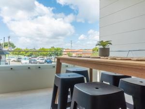 a balcony with stools and a view of a parking lot at Rockpools 1 in Sawtell