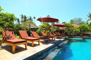 a group of chairs and umbrellas next to a swimming pool at Mega Cottages in Nusa Lembongan